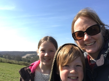 Kate with her two children taking a selfie on top of a hill.