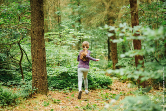young girl running through woodland 