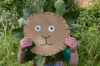 cardboard circle with a lion's face drawn on and leaves glued around the circle to look like a lion's mane.