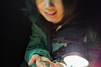 Student holding newt with torch shining on it