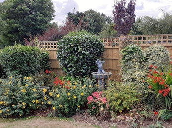 Statue of woman bathing is the water feature in this garden.