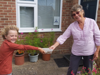 Boy handing over transaction from plant sale in socially distanced manner