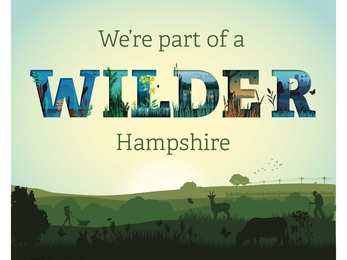 Sign saying "we're part of a Wilder Hampshire" where "WILDER" lettering is stylised.