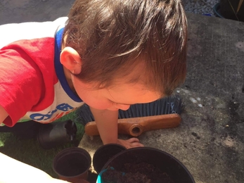Young boy holding space and shovelling soil into a flower pot