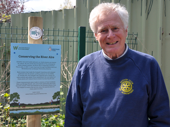 Jon Pittam of Alresford Rotary Club with sign celebrating chalk stream habitat restoration © Hampshire & Isle of Wight Wildlife Trust