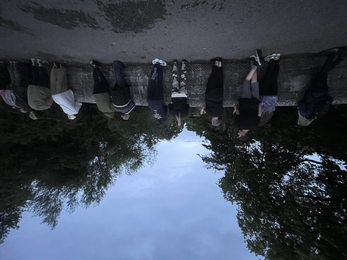 12 people looking over the side of a stone bridge at dusk
