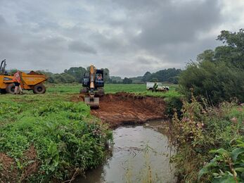 A digger carrying excavation work on a stretch of narrow river