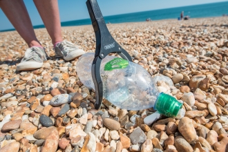 Picking up a plastic bottle on a Hayling Island beach clean organised by Southern Co-op