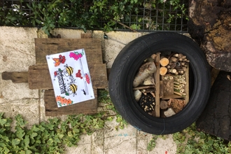 Bug hotel (stacked twigs, logs, etc) inside reused car tire