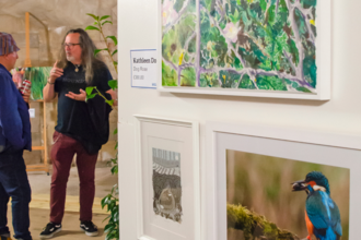 Wilder Art Exhibition, two people talking in front of some art work