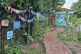 Polygon Orchard - path leading up to mural with native flowers, bug hotel is featured on fence