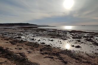 Thorness Bay intertidal zone. Sun glistening down on the rocks, sea and seaweed