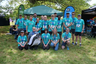 All runners in running shirts and medals in front of trust branded banners 