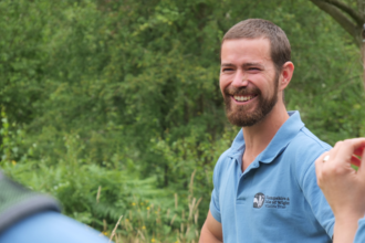 staff member in teal uniform, close up smiling at camera 