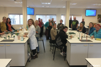 A large group of volunteers sitting around two lab tales sorting and counting seagrass seed.
