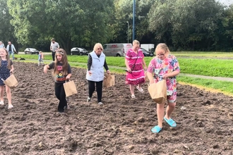 Parents and childred sow wildflower seeds
