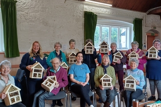 Group of people holding up their their bug hotels that they have made
