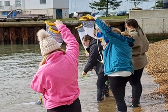 Group of adults on the beach standing in shallow water with Plankton nets
