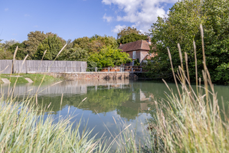 A body of water with a brick building in the near background on a sunny day 