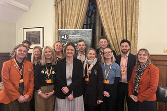 12 people standing for a photocall at a parliamentary event 