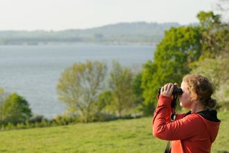 Young woman birdwatching at Rutland Water