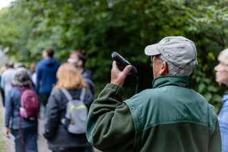 Man holding a bat detector up listening for bats