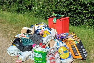 a bile of collected and bagged litter by an outdoor bin