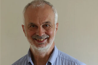 Headshot photo of a man in a blue shirt 
