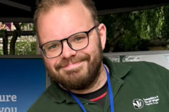 Man with glasses on, looking at the camera smiling. 