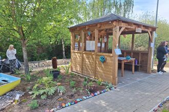 An outdoor wooden structure with a herb garden next to it on a sunny day