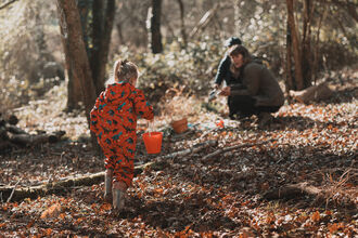 Girl carrying a bucket of water to her family in a woodland.