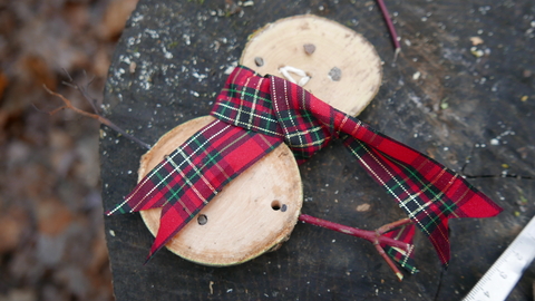 Wood slice snowman with a ribbon scarf and stick arms.