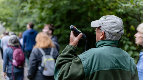 Man holding a bat detector up listening for bats