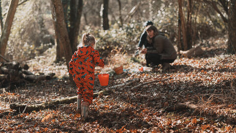 Girl carrying a bucket of water to her family in a woodland.