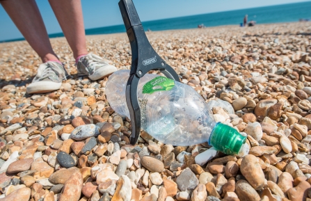 Picking up a plastic bottle on a Hayling Island beach clean organised by Southern Co-op