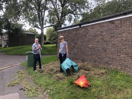 Two volunteers raking grass area to prepare for Wildflower community plot