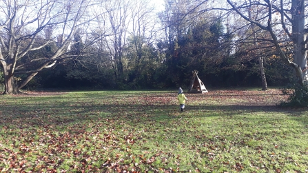 Boy exploring St James' Park and walking towards a log shelter