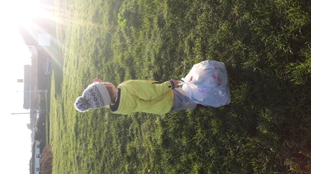 Boy looks into setting sun as he litter picks