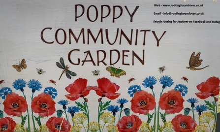 Signage board with words "poppy community garden" and group contact details.
