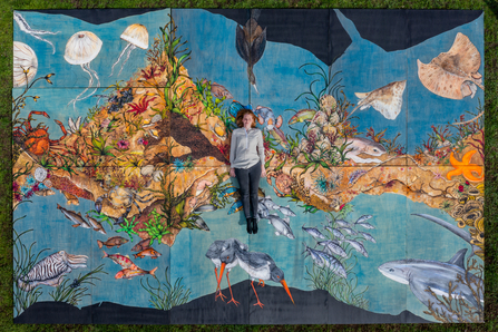 Hannah Horn, artist, laying on murals all pieced together