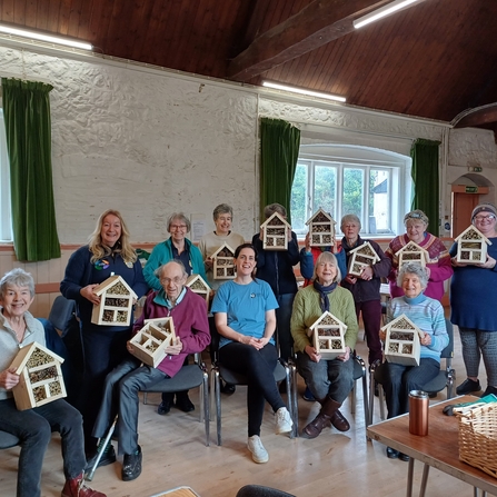 Group of people holding up their their bug hotels that they have made