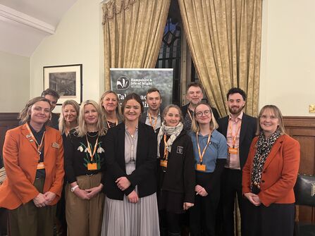 12 people standing for a photocall at a parliamentary event 