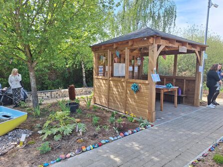 An outdoor wooden structure with a herb garden next to it on a sunny day