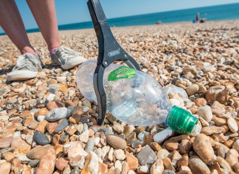 Picking up a plastic bottle on a Hayling Island beach clean organised by Southern Co-op