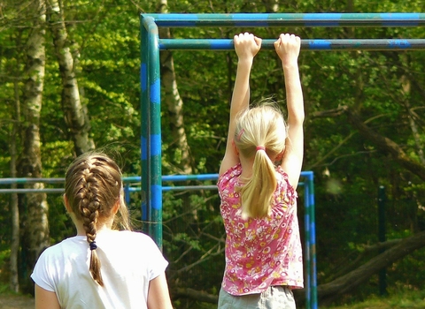 Girl hanging from monkey bars