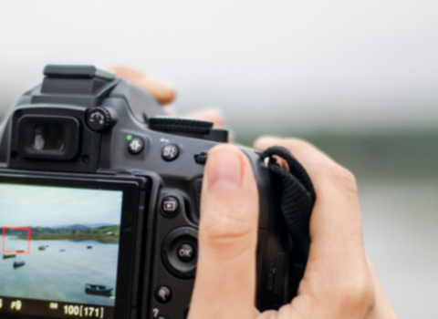person holding camera photographing coastal scene 