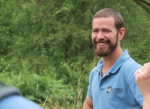 staff member in teal uniform, close up smiling at camera 