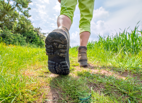 Person walking on green grass track in walking boots. Photo shows the bottom of the walking boot.